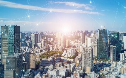 「都市とデジタルネットワークが融合するスマートシティのイメージ。クラウドシステムやデータセンターを活用した安全なビジネスインフラソリューションを提供。