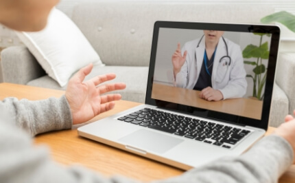 A patient receiving online medical care on a laptop computer. Development of a telemedicine service system to help improve access to medical care and physician work efficiency.