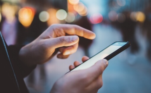 A hand operating a smartphone. solutions that support the evolution of cashless payment and digital communication using AI and IoT technologies.