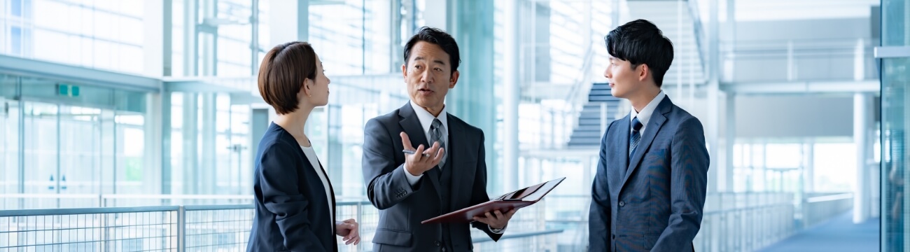 オフィスビル内で製品やサービスの説明を行うビジネスパーソンたち。主要製品・サービスに関する商談や提案のイメージ