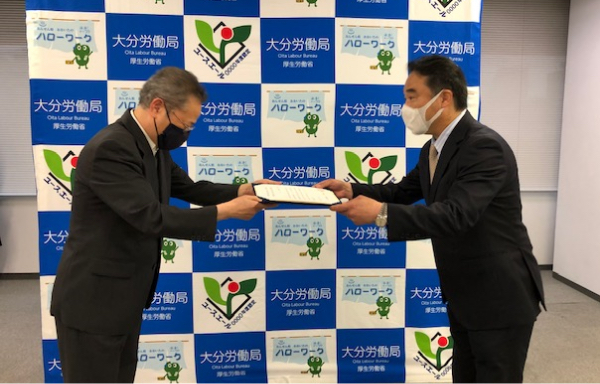 OMRON Taiyo President Ikuo Tateishi (Right) Accepts the Letter of Certification from Akihiko Nakayama, the Director General of the Oita Labour Bureau (Left).