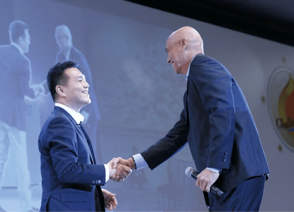 当時のオムロン株式会社 代表取締役社長 CEO 山田義仁とオムロン マニュファクチャリング オブ インドネシア社長のイラワン・サントソが握手している写真